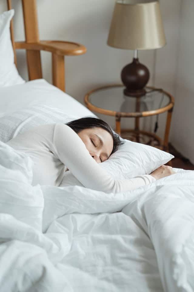 woman sleeping in bed with white bedding